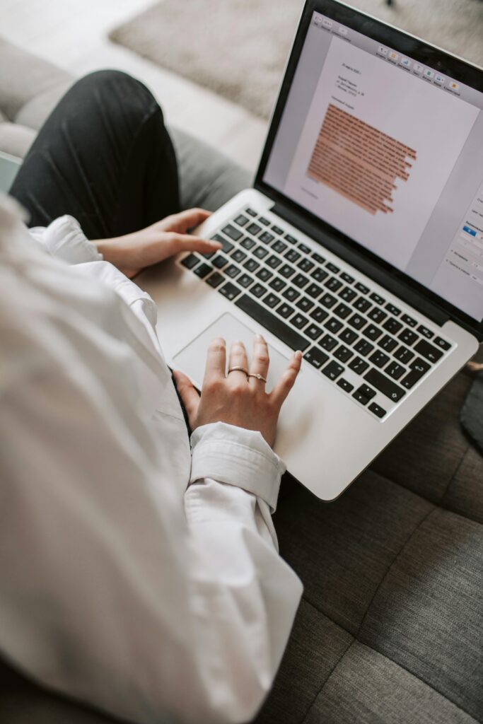 Person sitting on the sofa and editing a text on their laptop